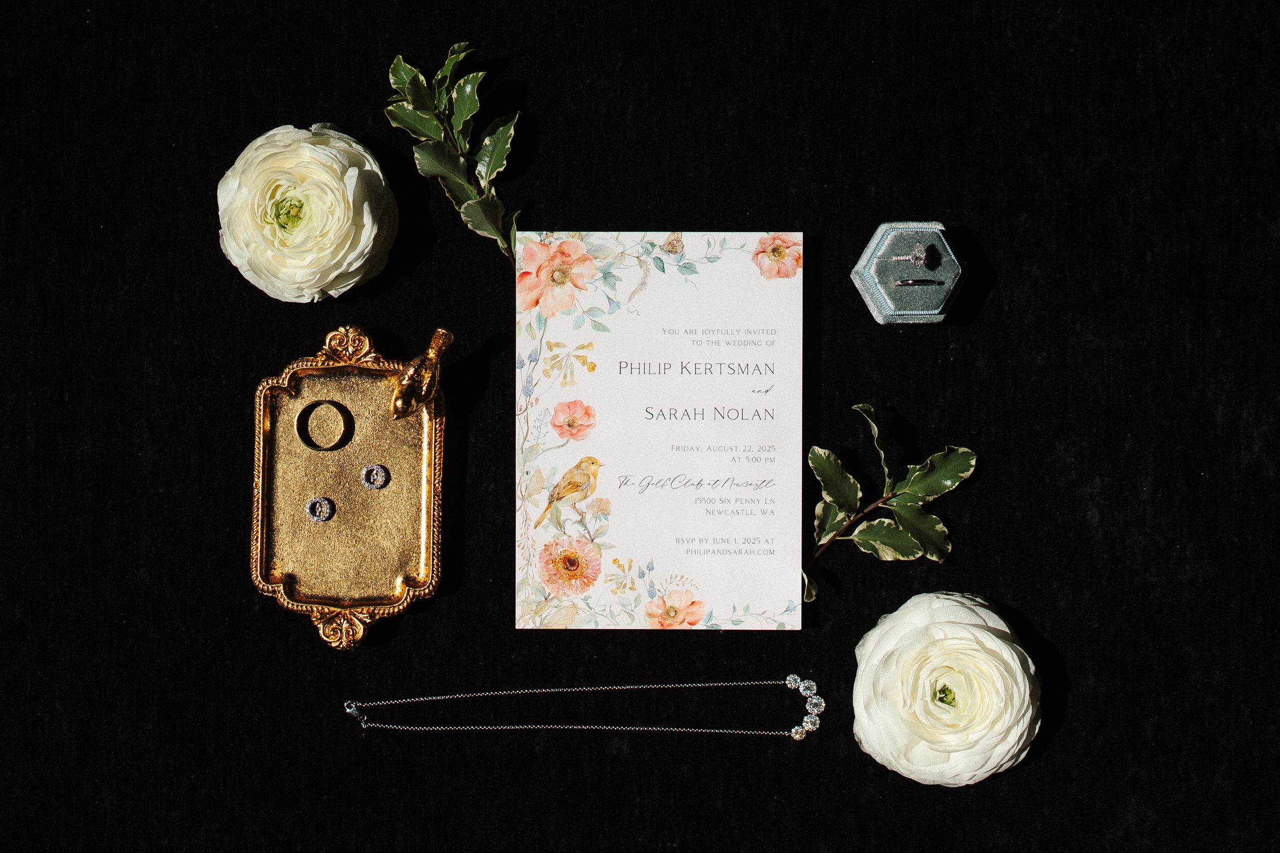 A collection of wedding invitation cards with floral designs, white ranunculus flowers, and vintage decorative elements.