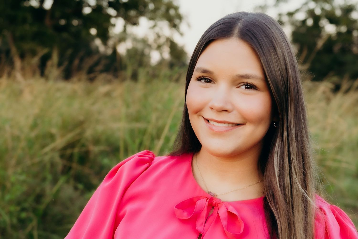 Portrait session in a sunlit field with pink clothing and natural outdoor backdrop.