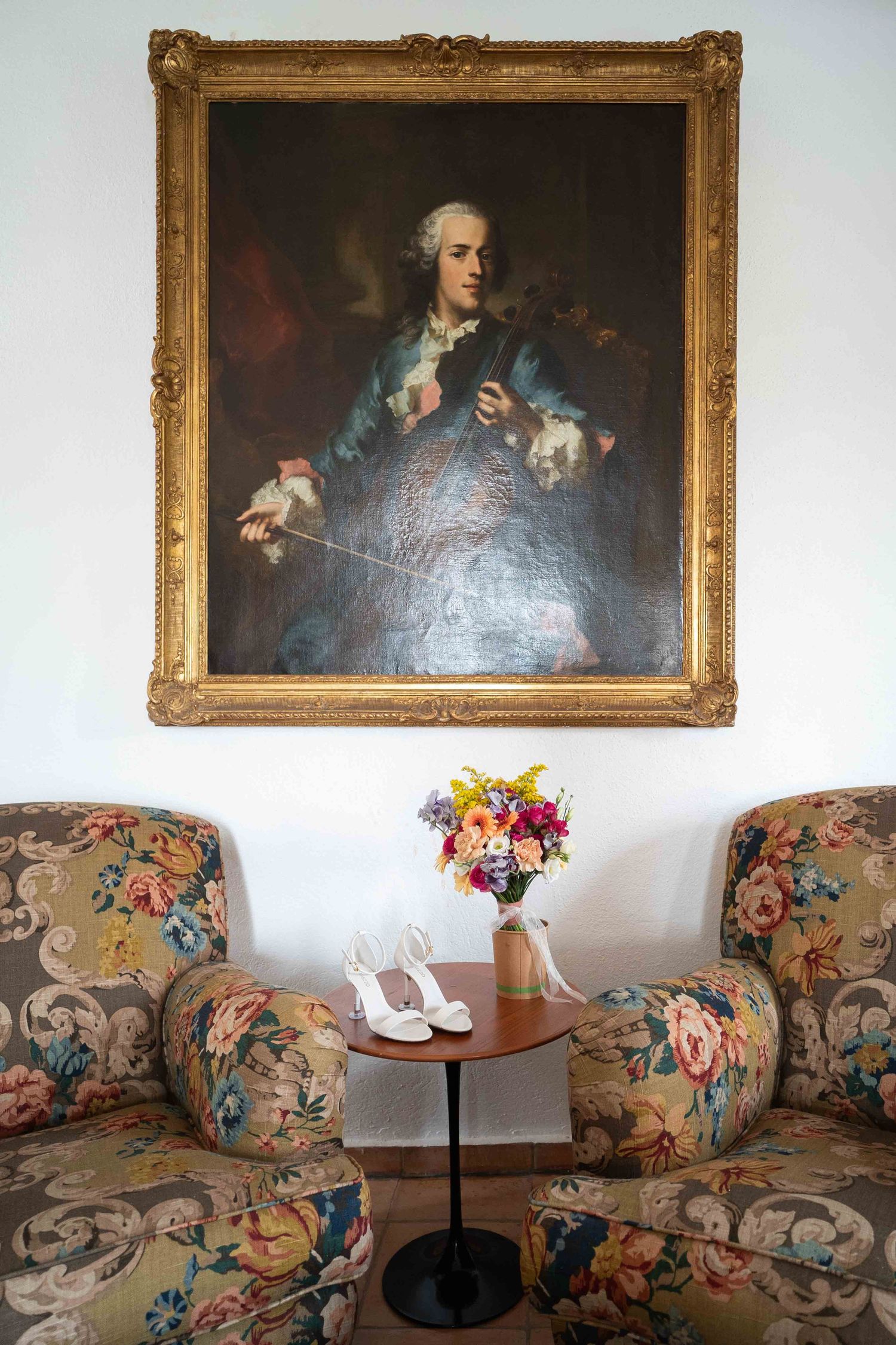 Elegant sitting area with vintage floral sofas and classical portraits in ornate gold frames.