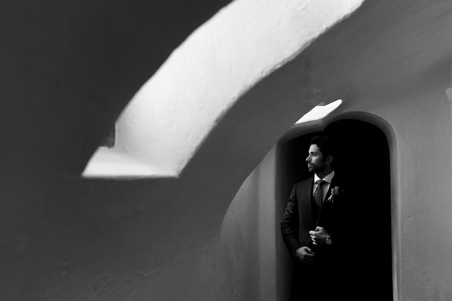 A dramatic black and white sequence shows a figure emerging from darkness into a stark white doorway.