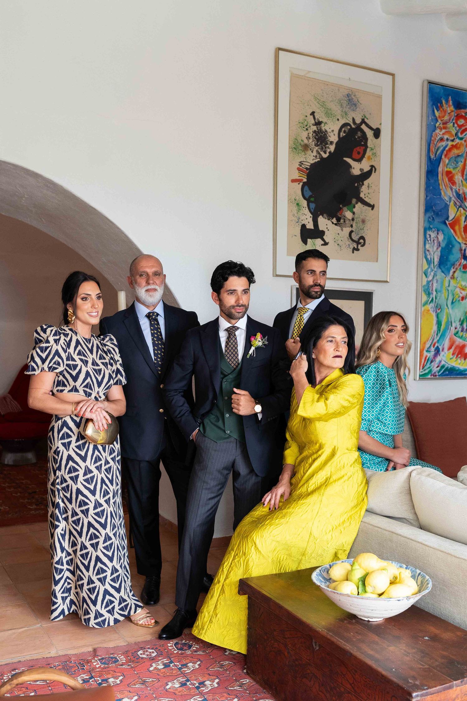 Wedding party members in formal attire gathered around a table with refreshments.