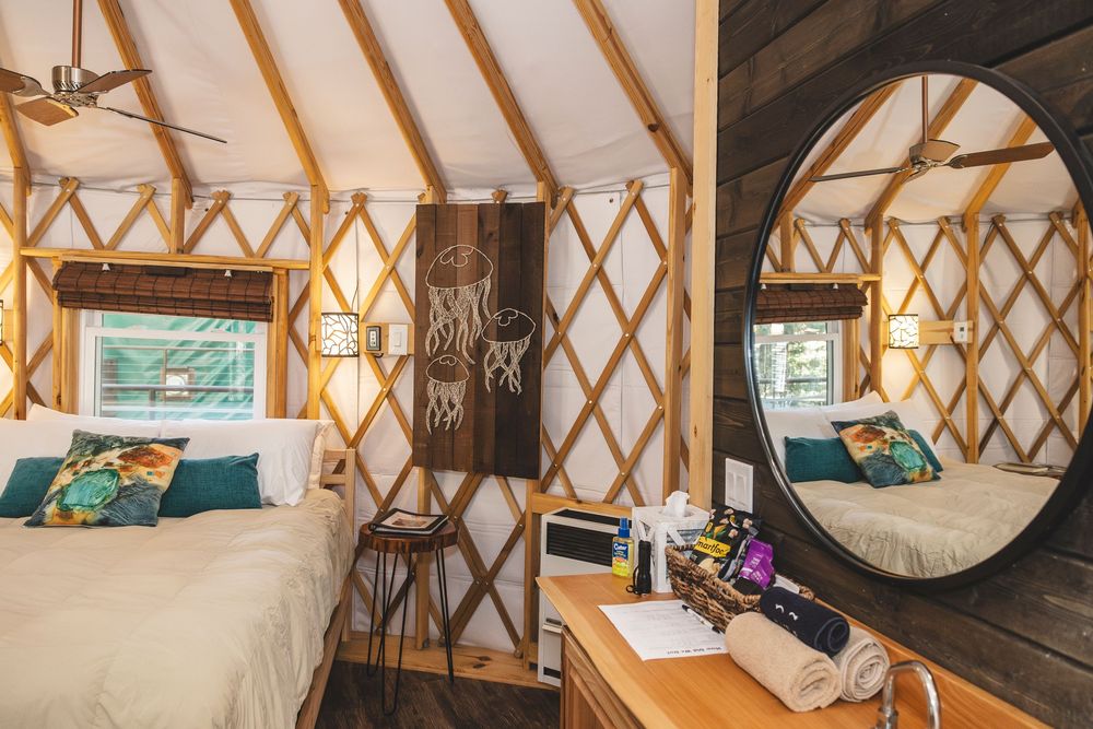 Interior view of a cozy yurt rental with rustic wooden furnishings and natural light streaming through windows.