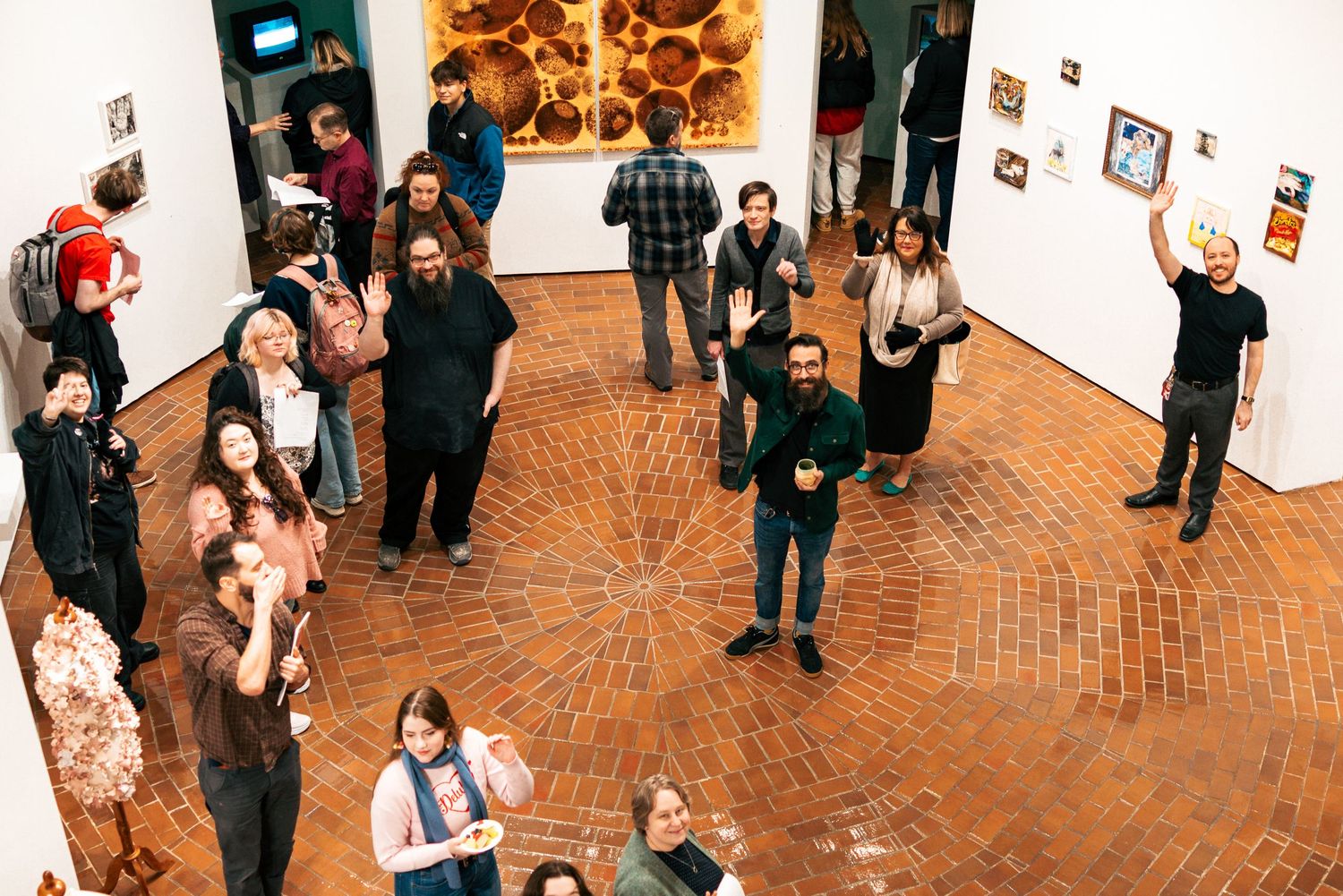 Art gallery visitors view framed photographs displayed on white walls during an exhibition opening.