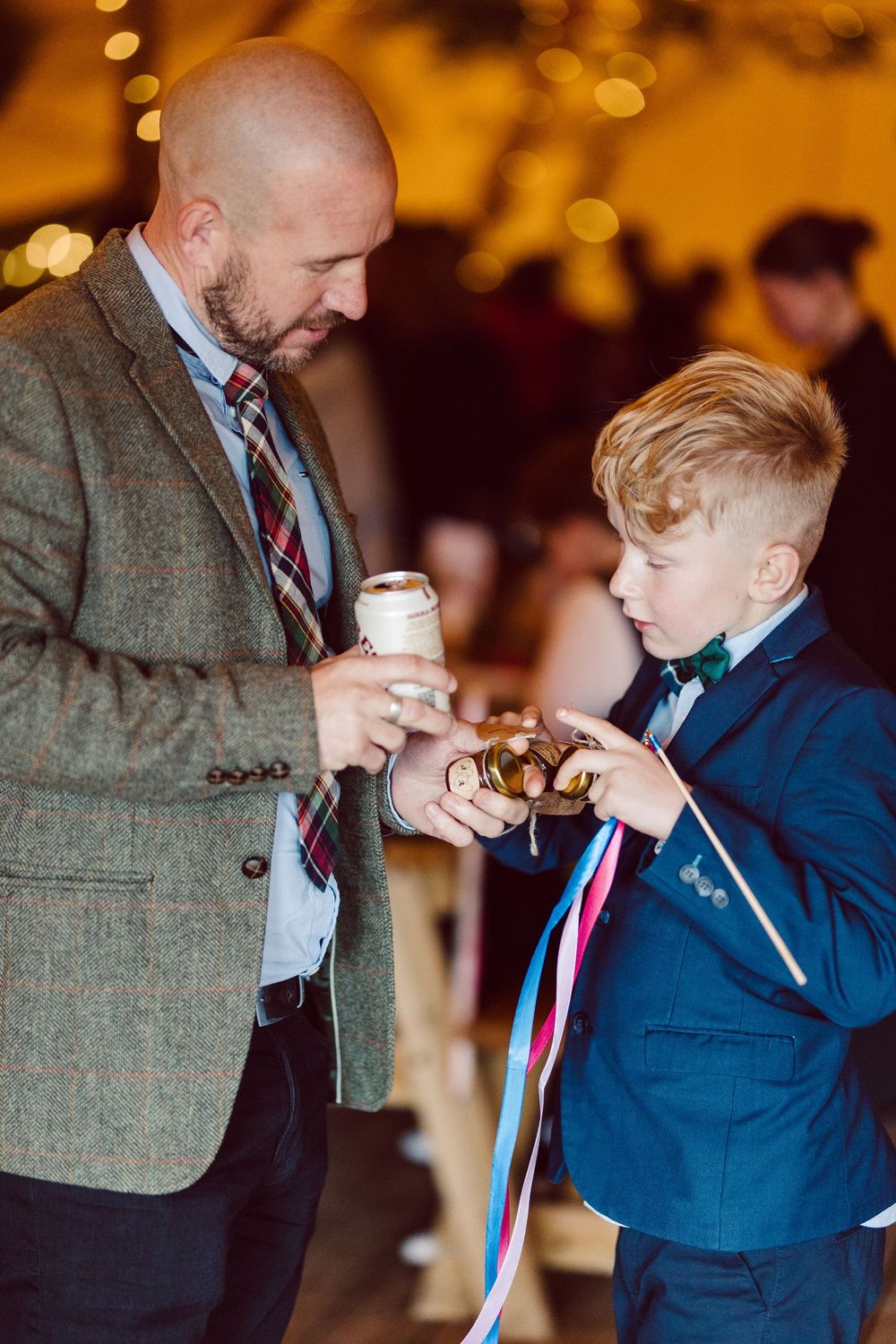 Two people share a tender moment during a formal event with warm glowing lights in the background.