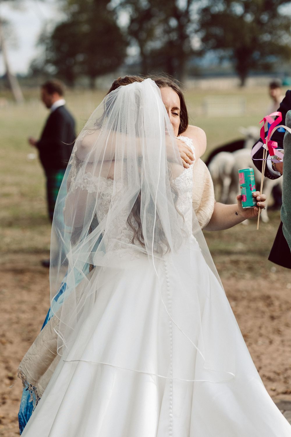 A flowing white wedding dress and veil catch the breeze in an outdoor setting during a wedding photoshoot.