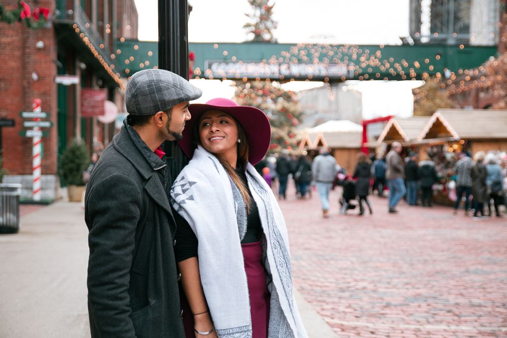 Couple sharing a romantic moment at an outdoor Christmas market in winter attire.
