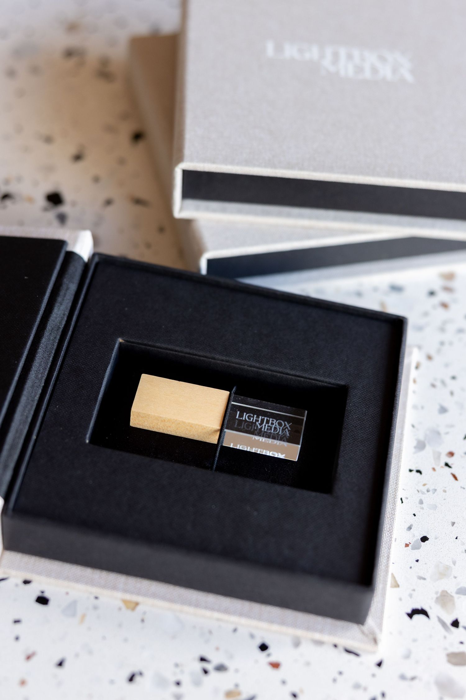 A series of black luxury gift boxes with gold metallic branding details shown in a progressive unboxing sequence.