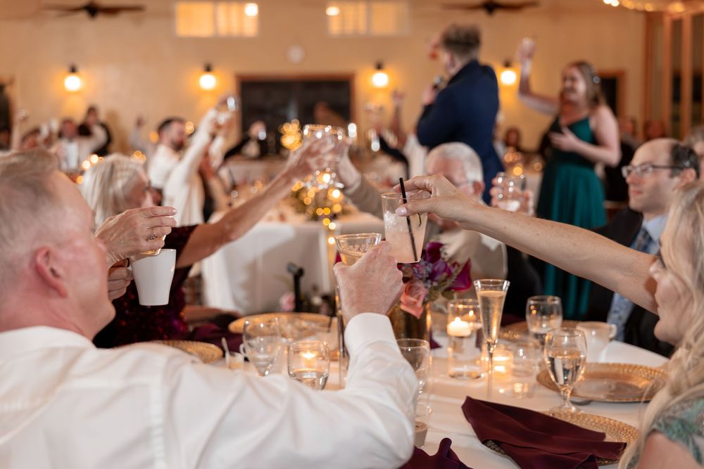 Wedding reception guests laugh and celebrate at elegantly decorated dining tables with glowing candlelight.