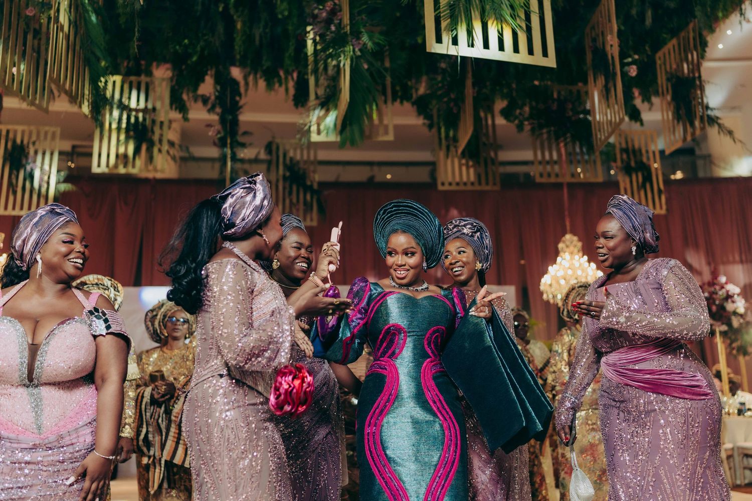 A group of people in formal attire celebrating at a wedding reception with joyful expressions and dancing.