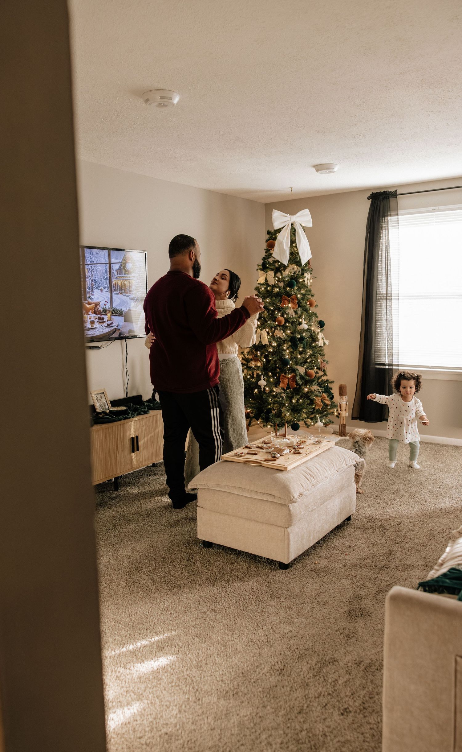 A sequence of photos showing a couple dancing in their living room near a decorated Christmas tree.