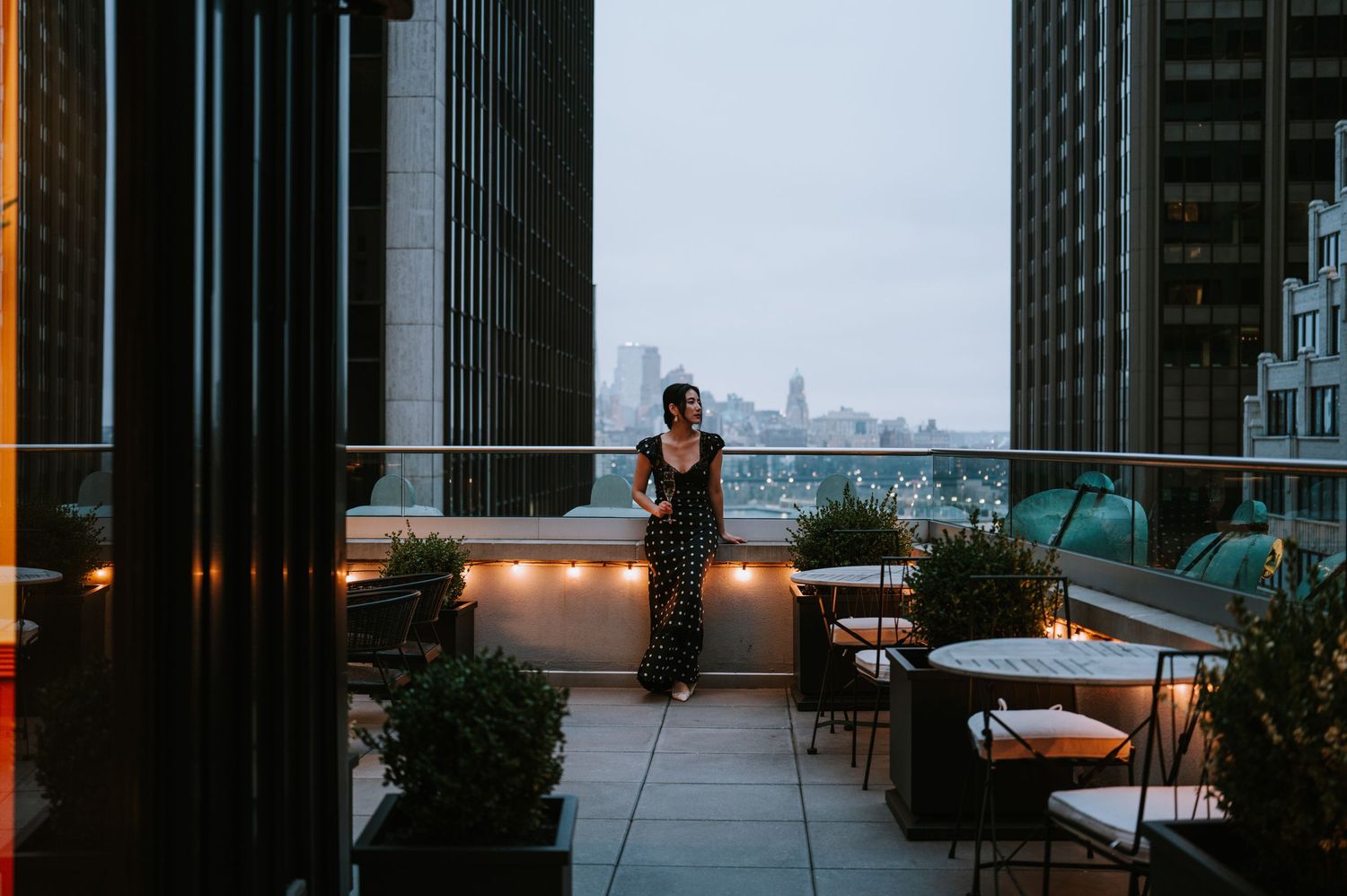 Woman sipping on champagne on a downtown New York City skyline hotel rooftop