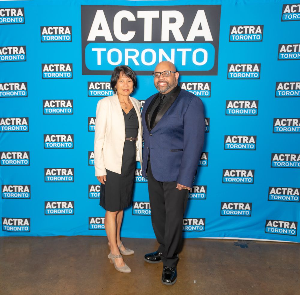 People standing at a media event with ACTRA and Toronto logos on a blue backdrop wall.