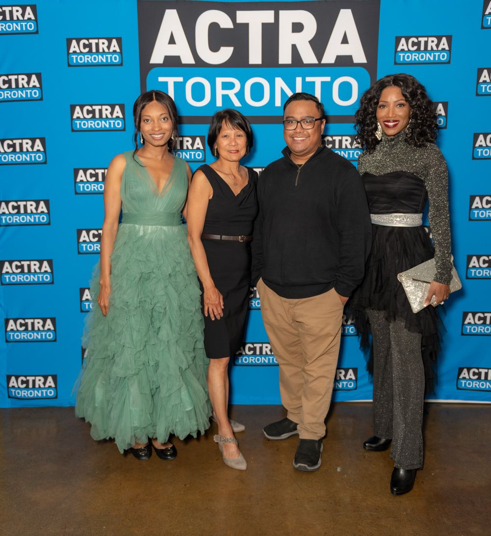 A group of people pose together against a blue ACTRA backdrop at an event.