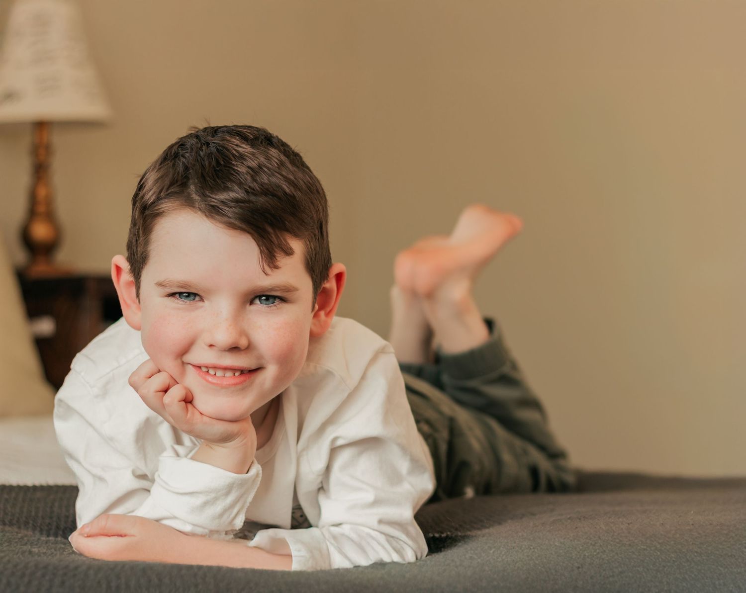 A young child in a white shirt lies on their stomach  |  Annual Birthday Photos for Kids
