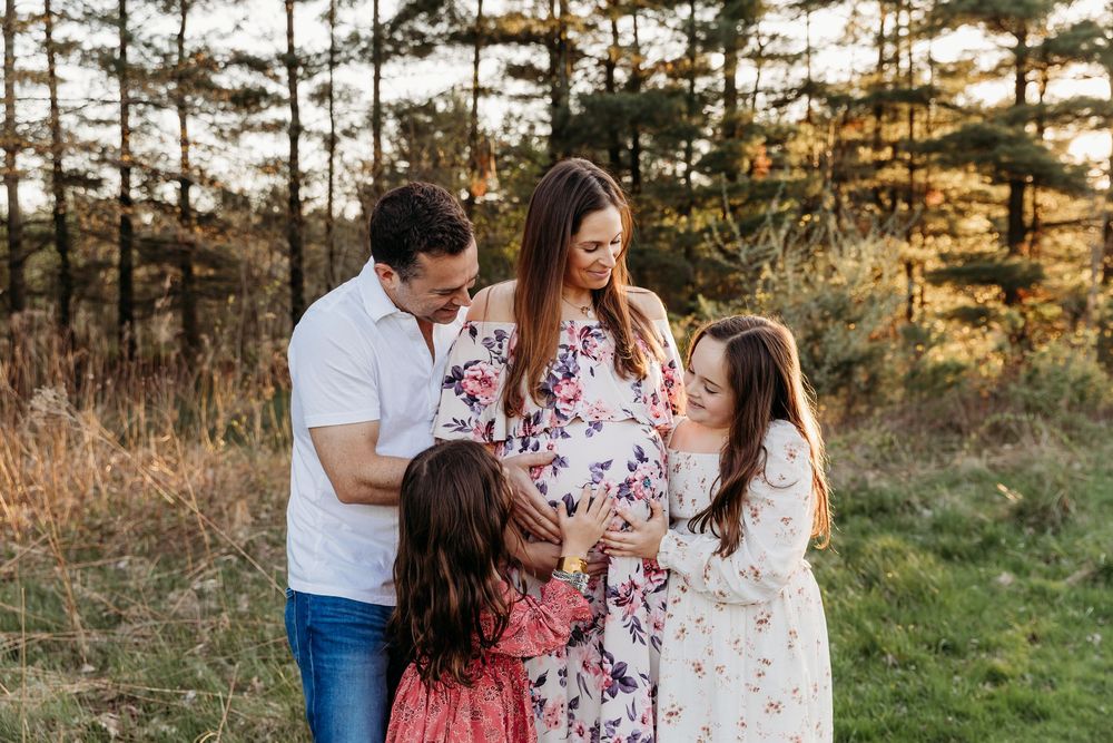 A family shares joyful moments together during a golden hour photo session in a pine forest setting.