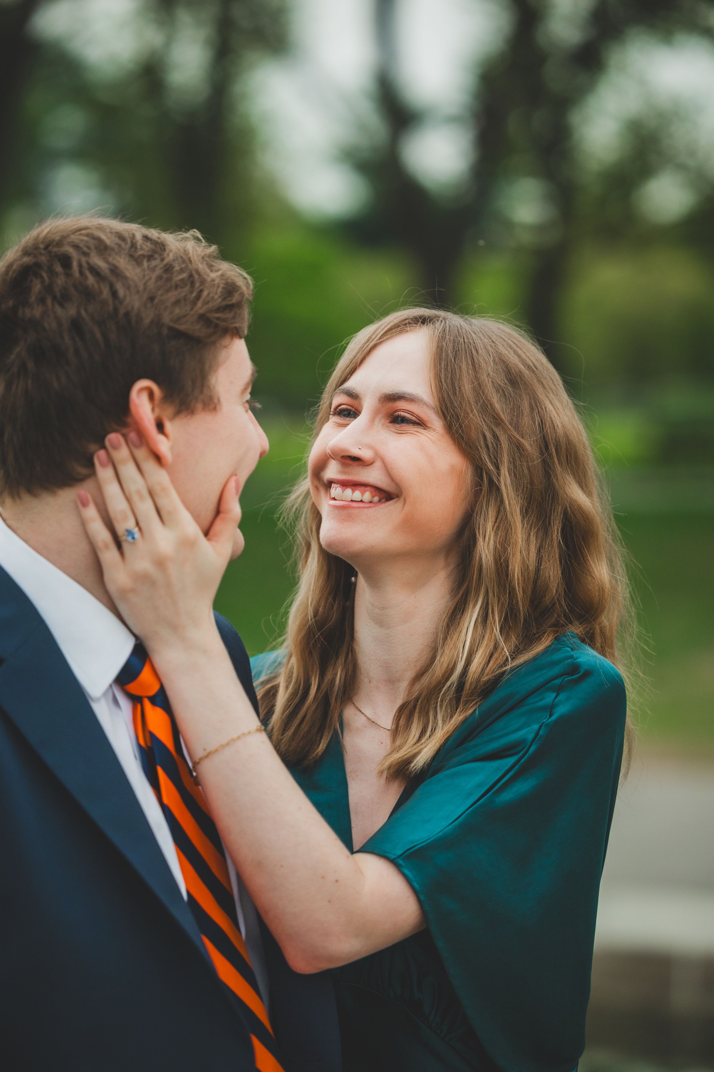 A couple shares tender moments in a series of intimate outdoor photos wearing navy and teal against a green background.