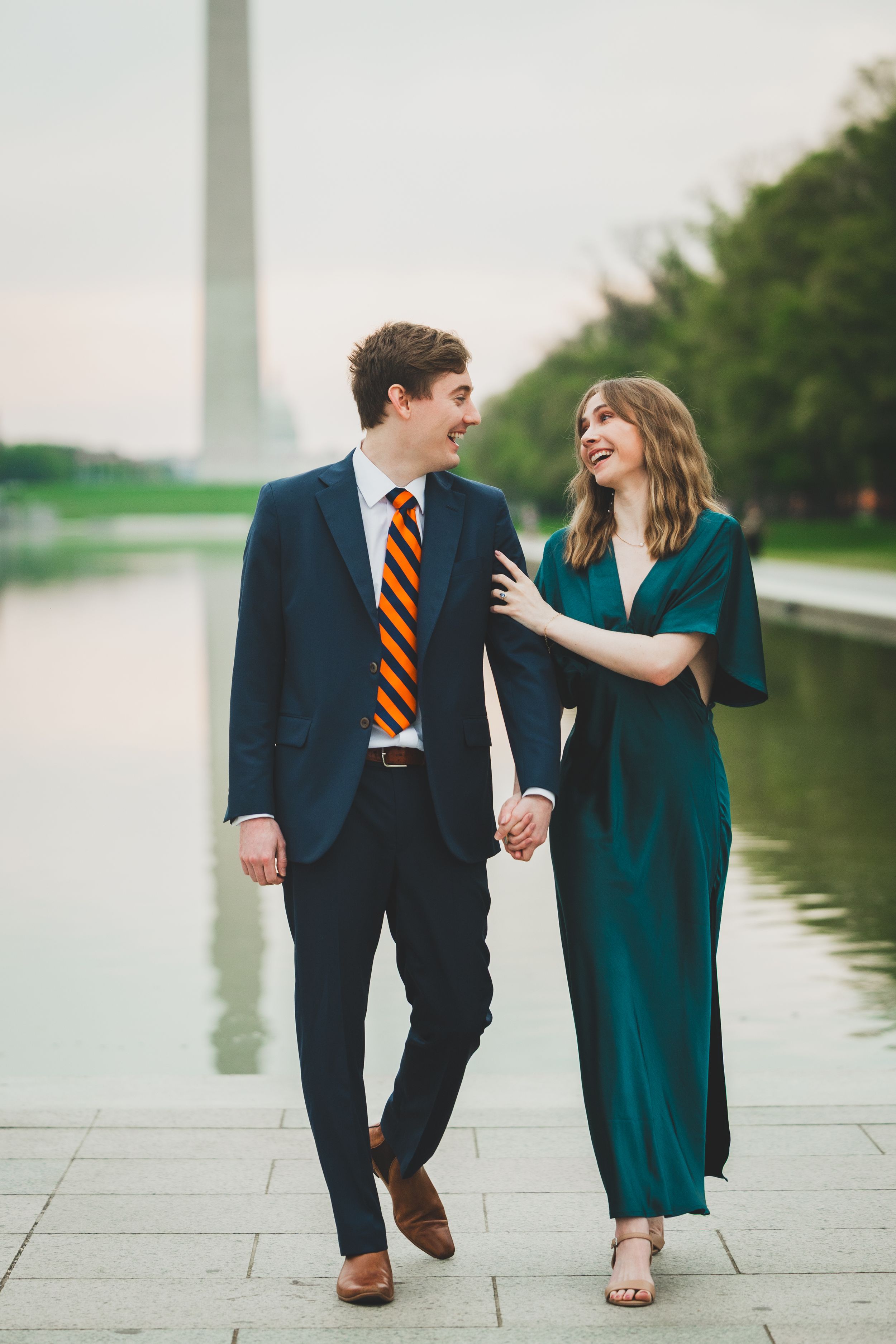 A couple walks hand in hand along the reflecting pool at the National Mall in Washington DC, sharing joyful moments together.