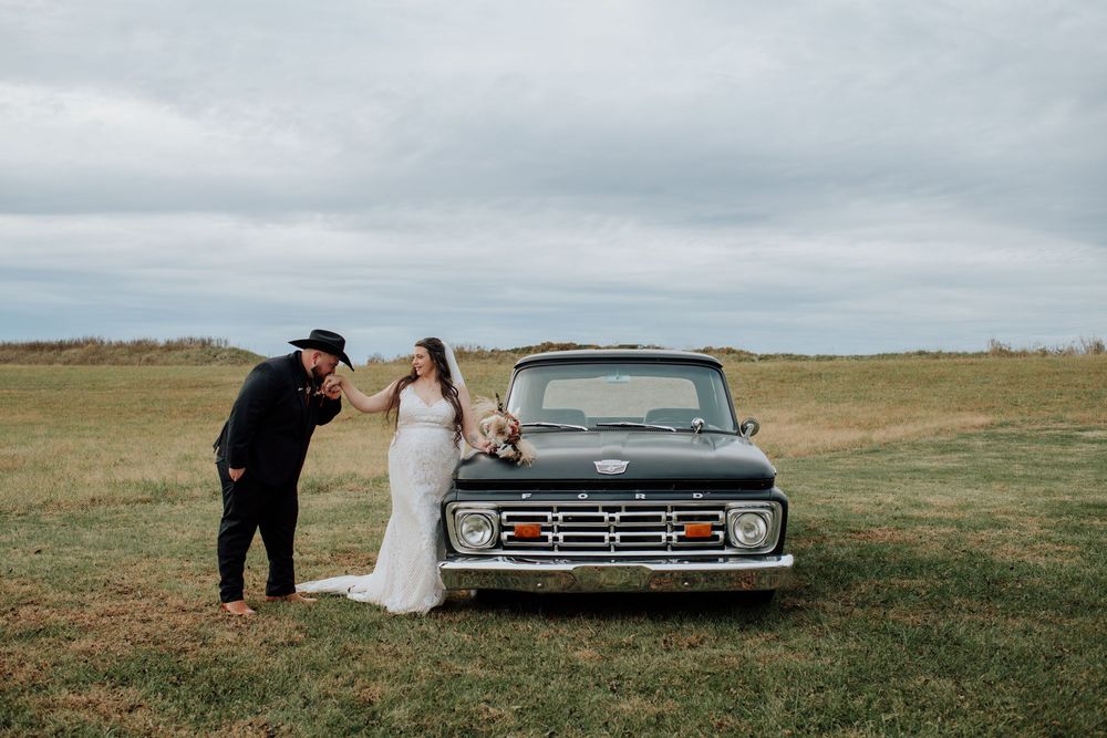 Couple celebrating western-themed wedding at rustic barn in Tennessee with vintage truck