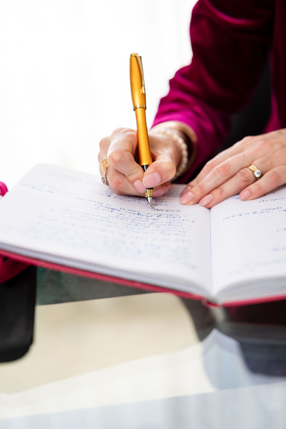Close-up of hands writing with a gold pen on paper documents.