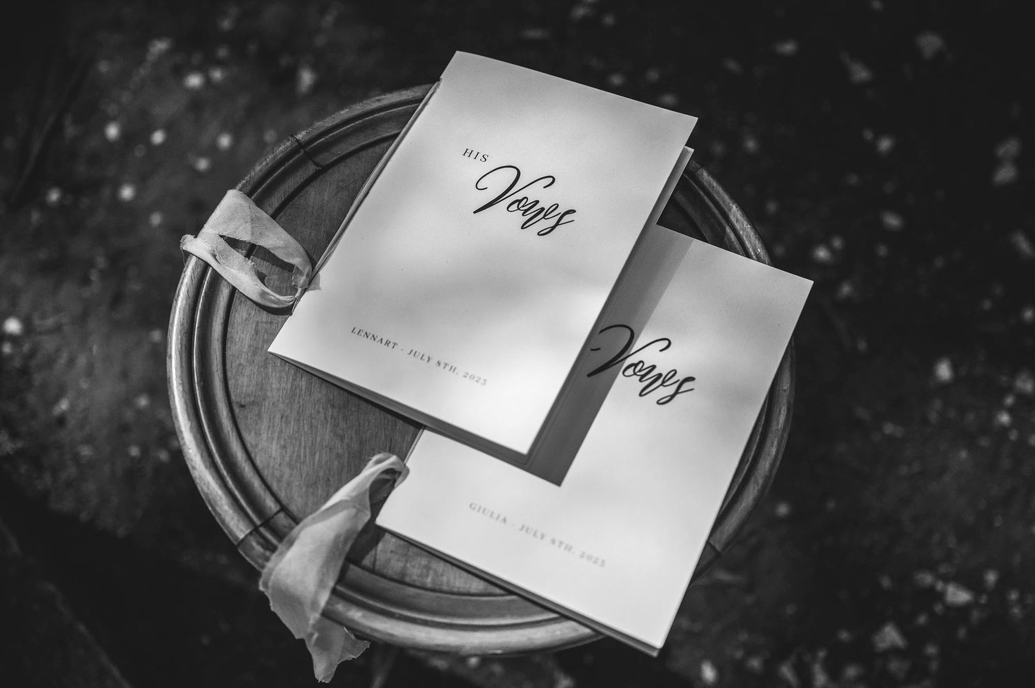 Wedding vow books displayed on dark textured surface with dramatic lighting.