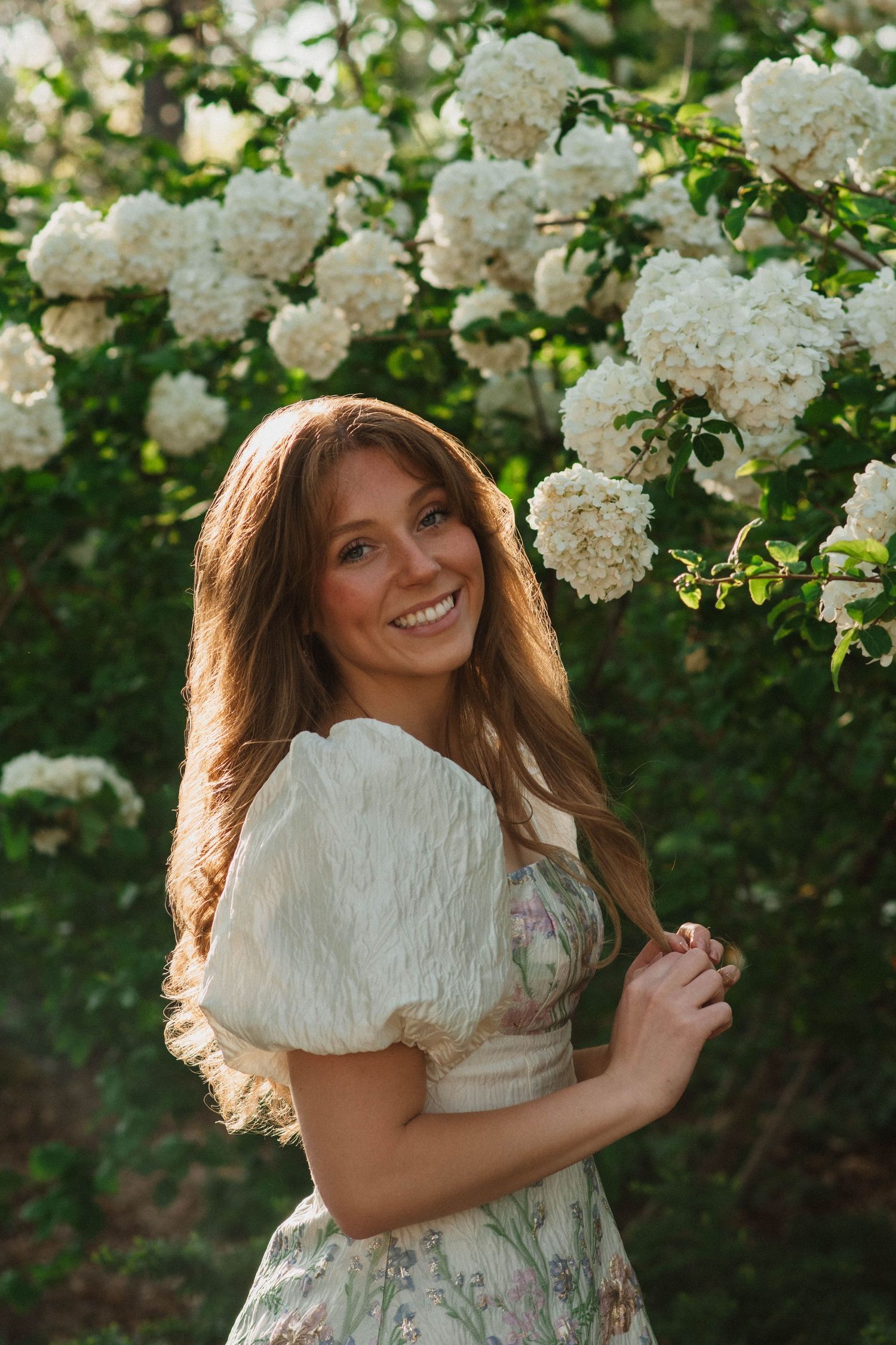 college senior posing in front of white hydrangeas at Myriad Botanical Gardens in Oklahoma City, Oklahoma