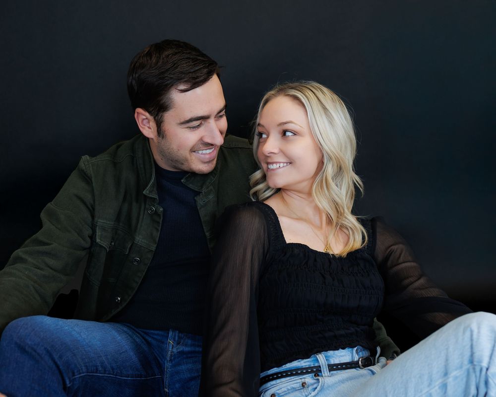 Romantic couple sharing intimate moments in dark setting during professional photo session.