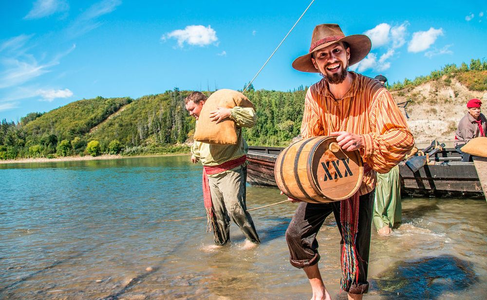 Two fishermen in traditional attire cast their lines into a serene lake on a sunny day.