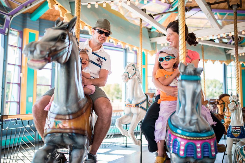 Families enjoying a vintage carousel ride with decorative horses at an amusement park.
