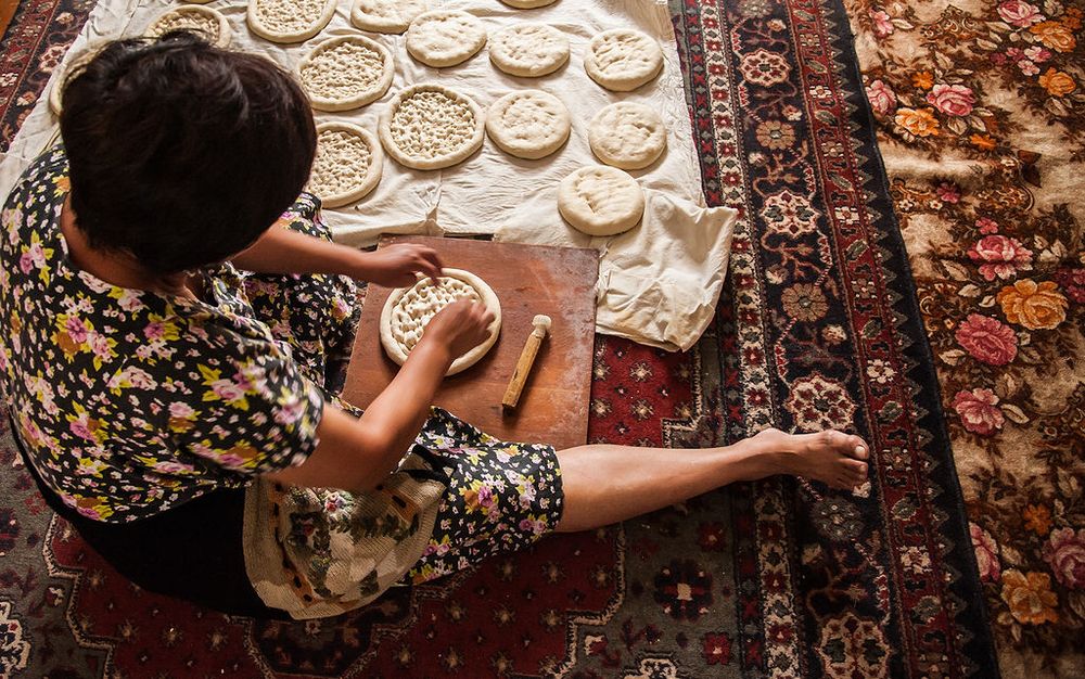 Overhead view of someone making homemade dumplings on a decorative rug.