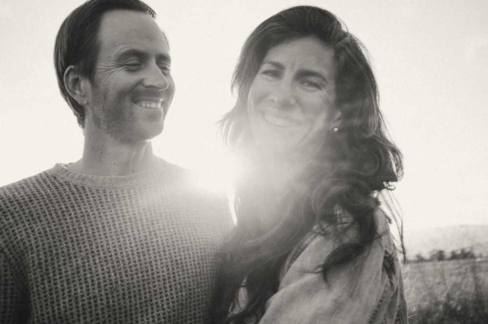 Romantic couple shares playful loving moments together outdoors in bright sunlight and lens flare.