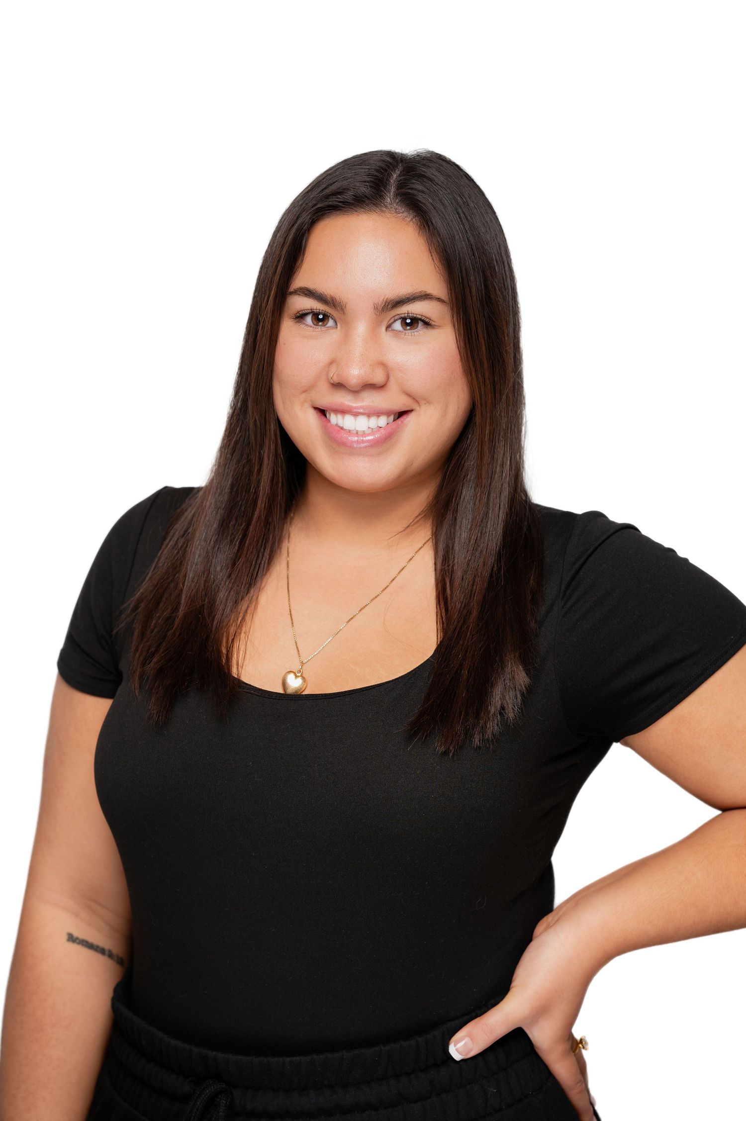 Professional headshot photo of someone wearing a black top and delicate necklace against a light background, smiling warmly.