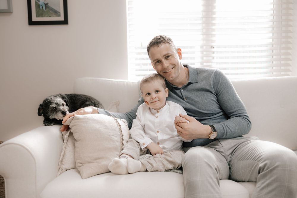 A cozy family moment on a white couch with a sleeping black dog laying nearby.