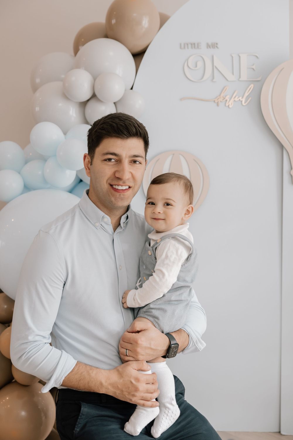 First birthday celebration backdrop with neutral colored balloon arch and party decorations.