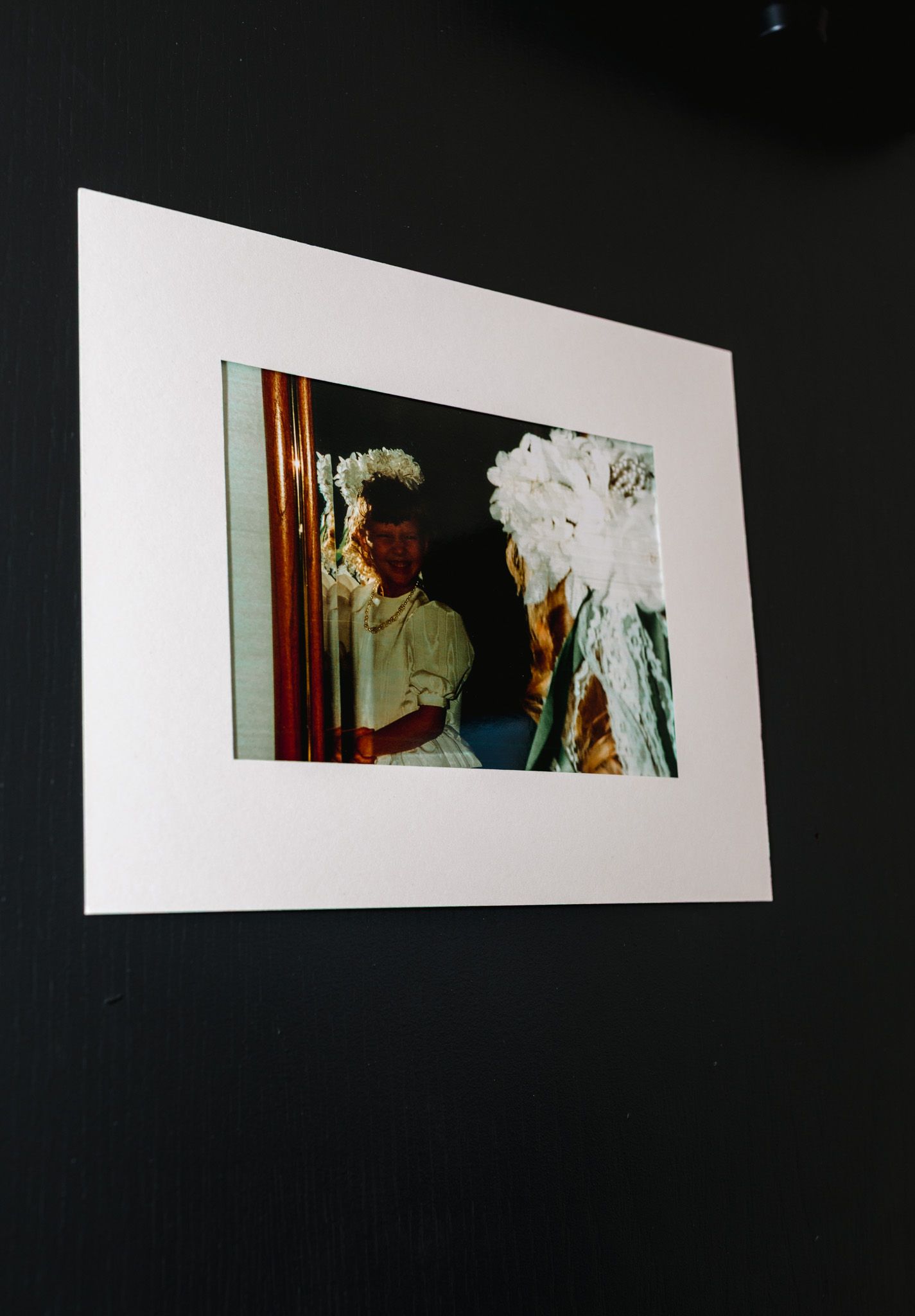 Vintage wedding photo matted in white frame mounted on dark black wall as decor.