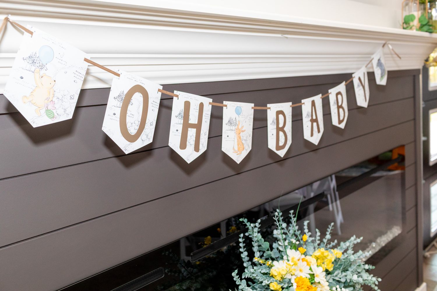 Oh Baby banner with woodland animal decorations hanging above a fireplace mantel.
