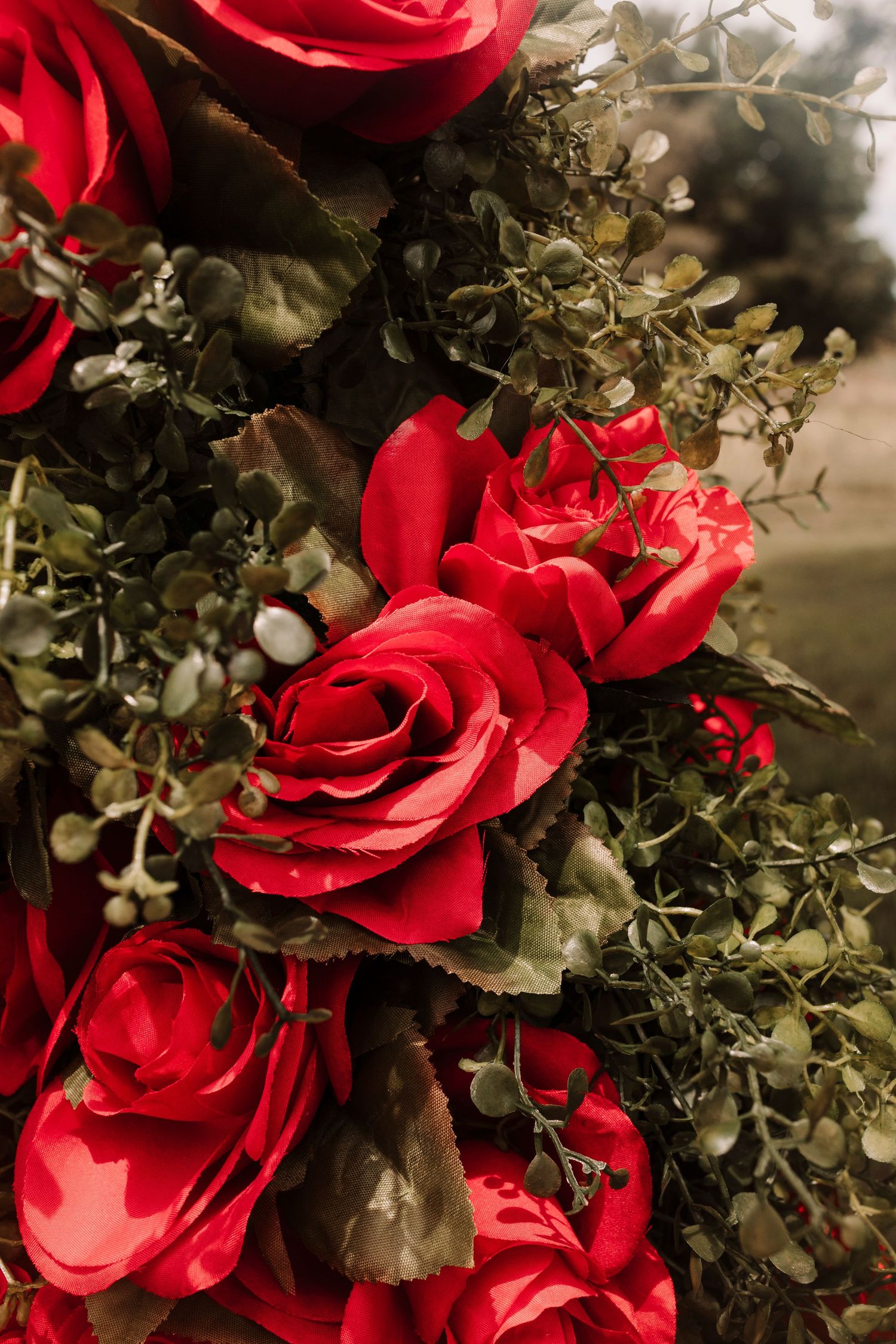 Close-up of vibrant red roses and green eucalyptus leaves in a lush wedding floral arrangement.