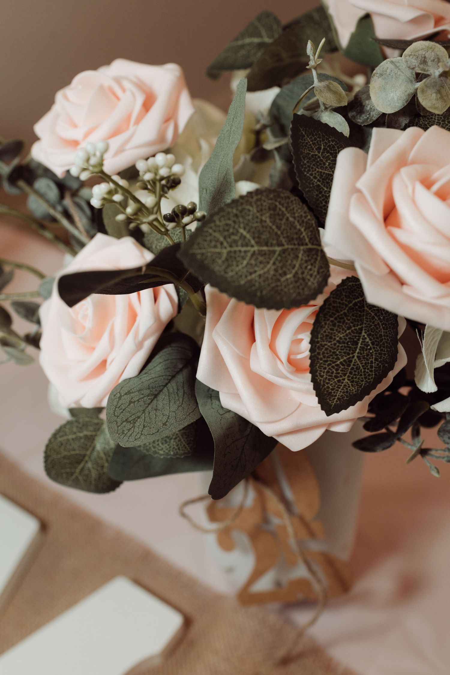 Elegant bouquet of blush pink roses with eucalyptus leaves and small white berries for a graduation party.