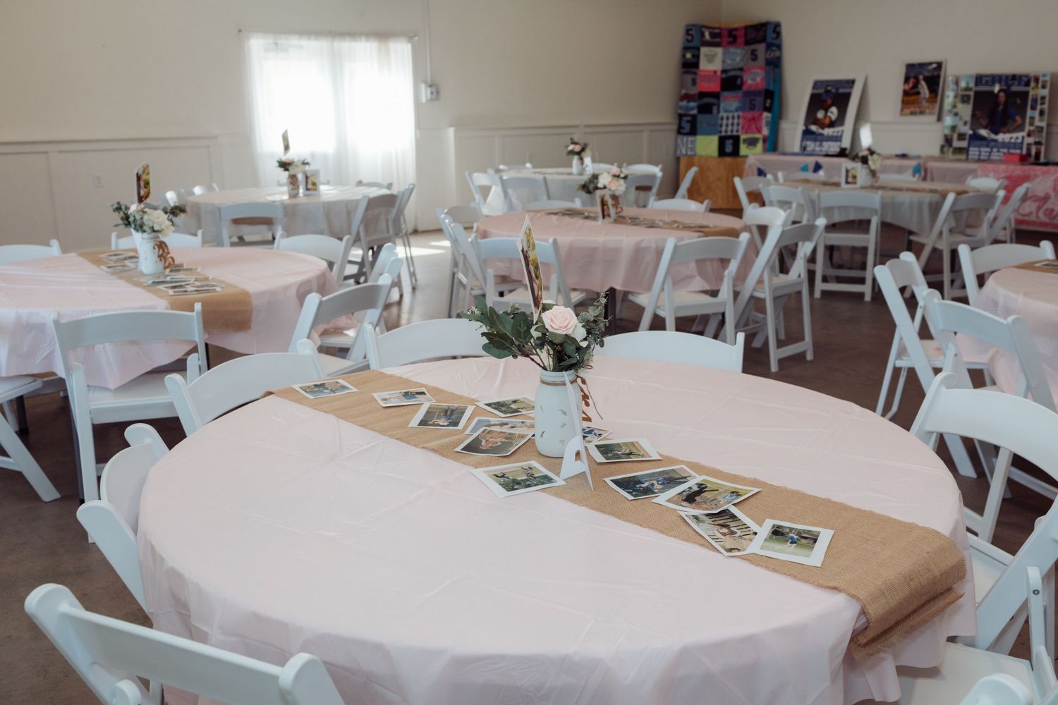 Elegant graduation party venue with round tables, white chairs, burlap runners, and floral centerpieces.