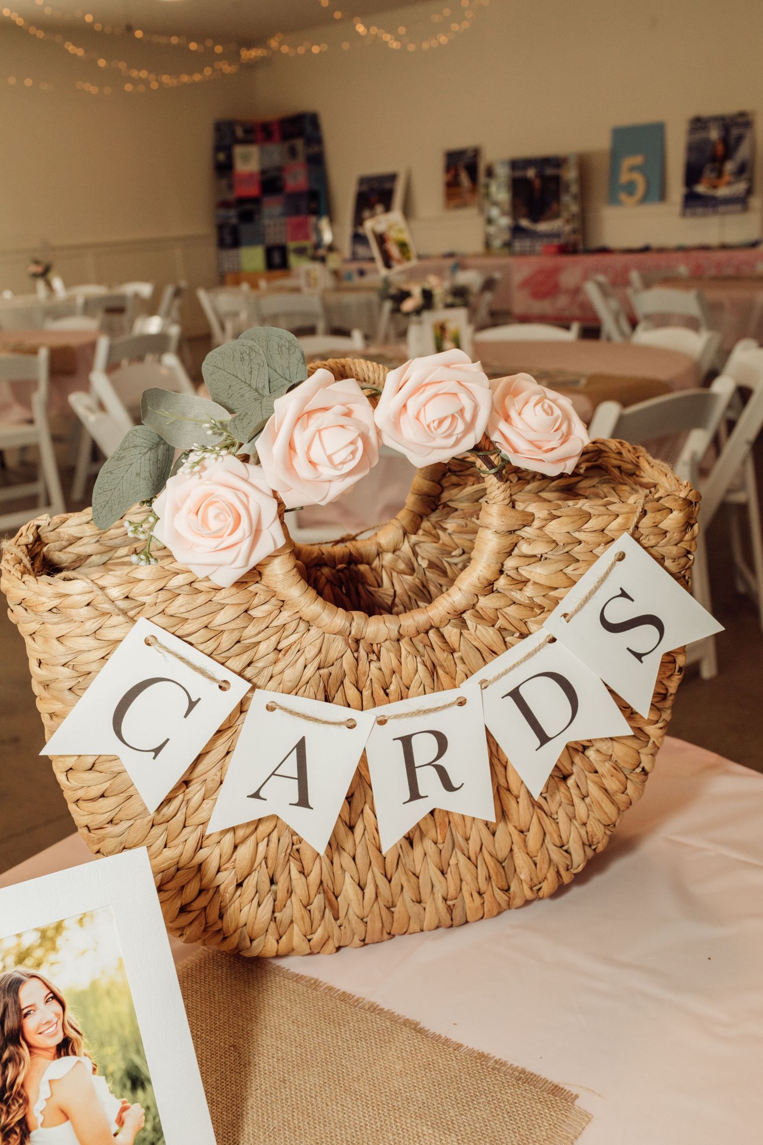 Wicker basket with CARDS burlap banner and pink roses for collecting graduation party greeting cards.