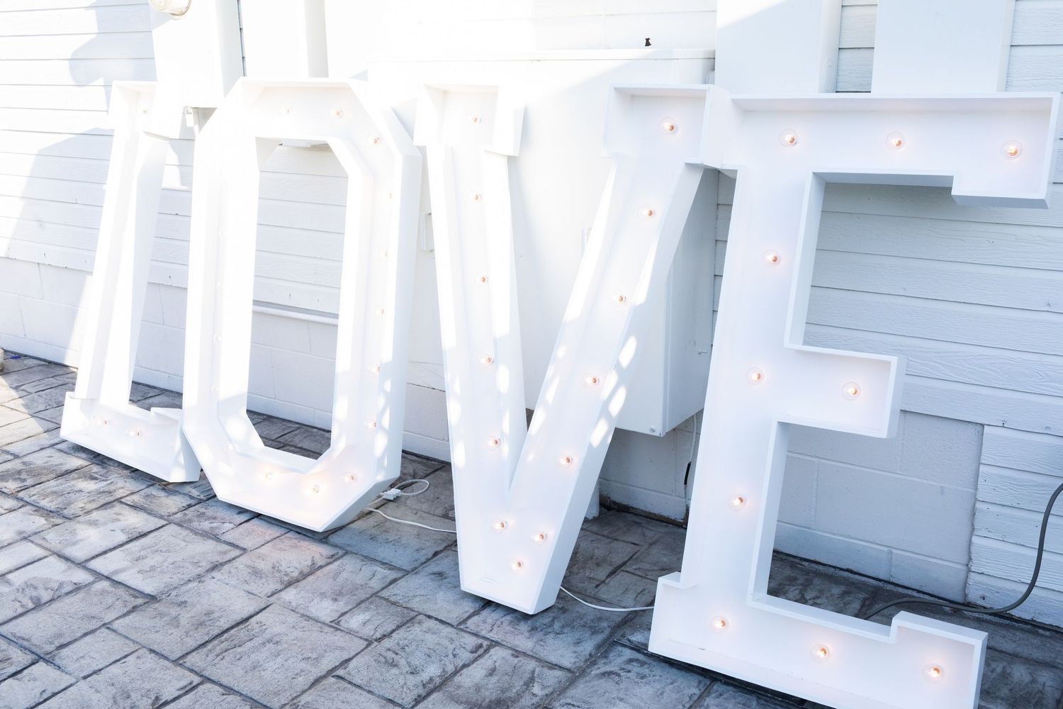 Large illuminated white LOVE marquee letters displayed outdoors at a wedding venue.