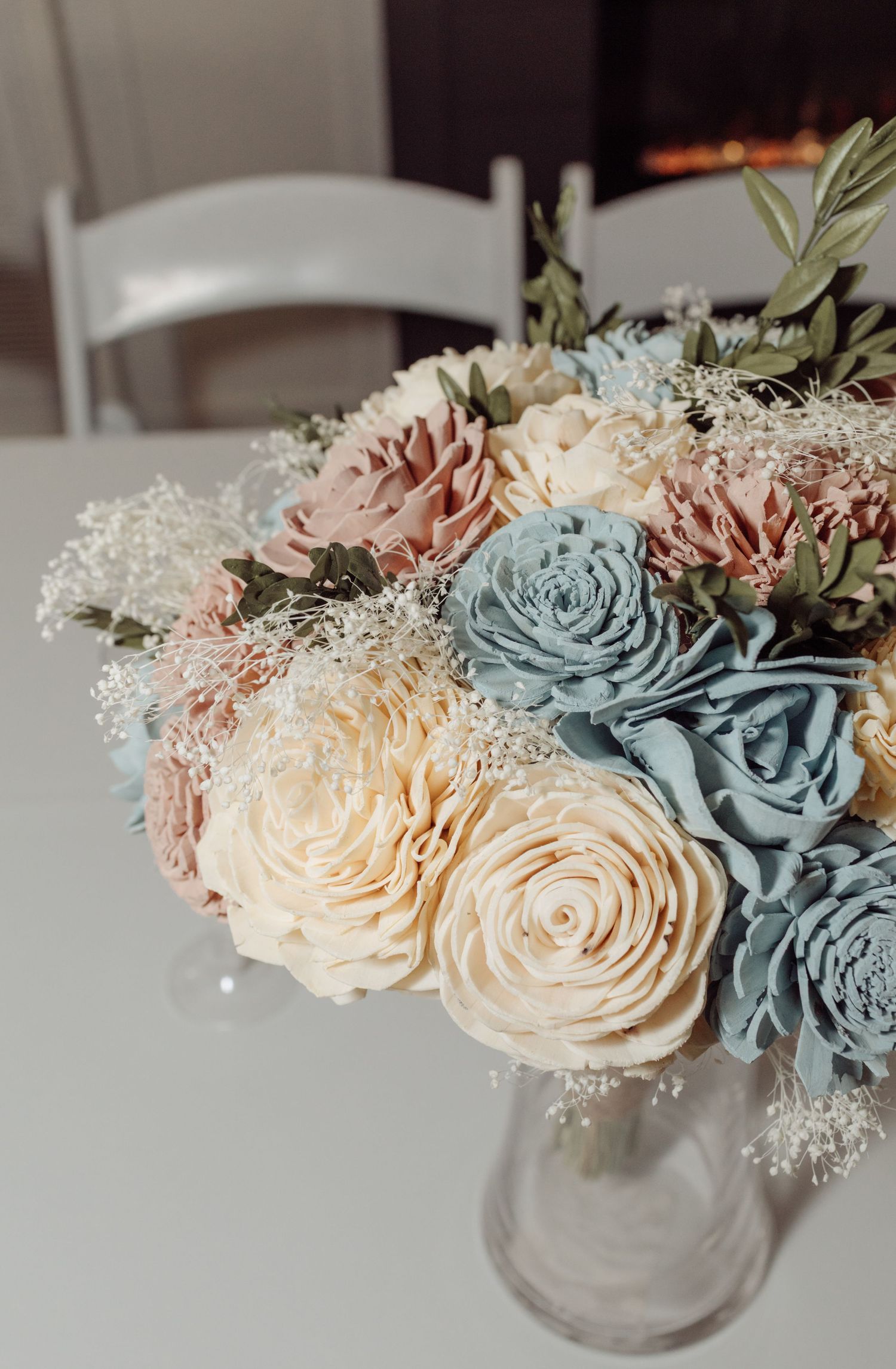 Soft pastel wedding bouquet with blush, cream, and blue sola wood flowers in glass vase.
