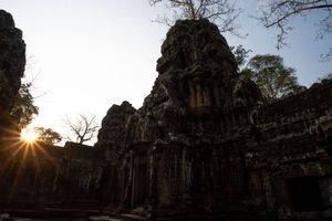 Ancient Angkor Wat temple towers silhouetted against bright sunlight.