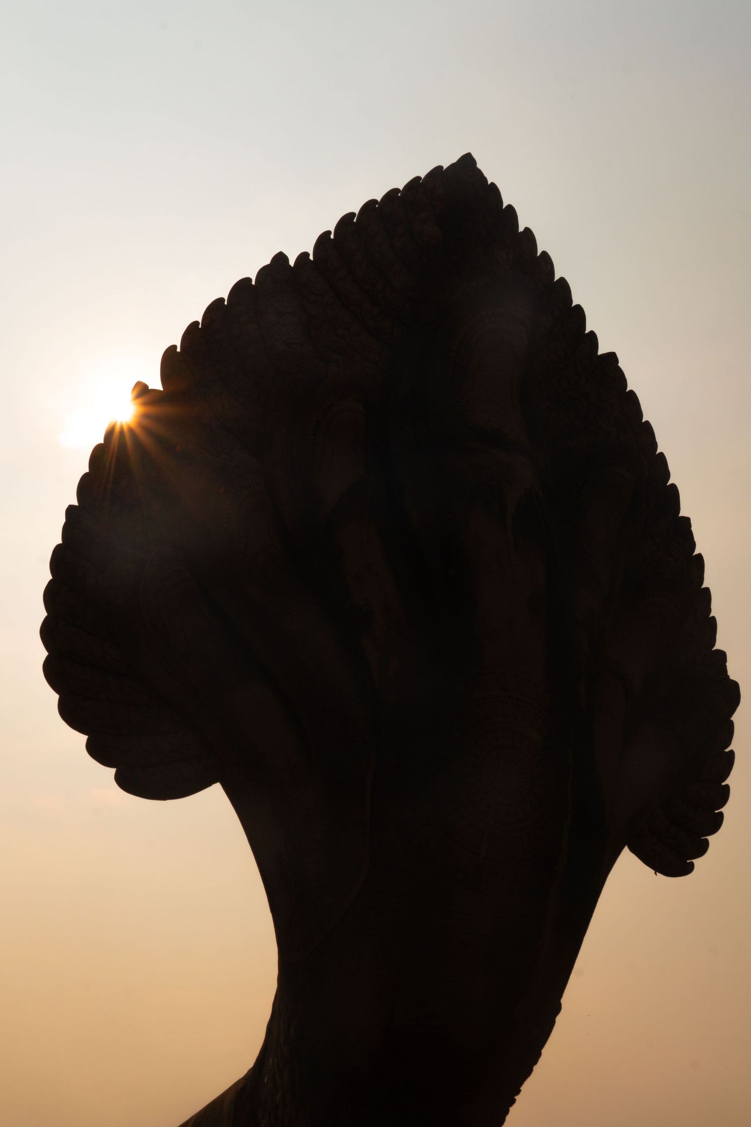 Silhouette of ornate temple architecture against bright sunlight.
