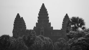 Ancient temple silhouettes of Angkor Wat against a misty sky in Cambodia.
