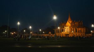 Illuminated temple building at night with crowds gathered in the foreground.