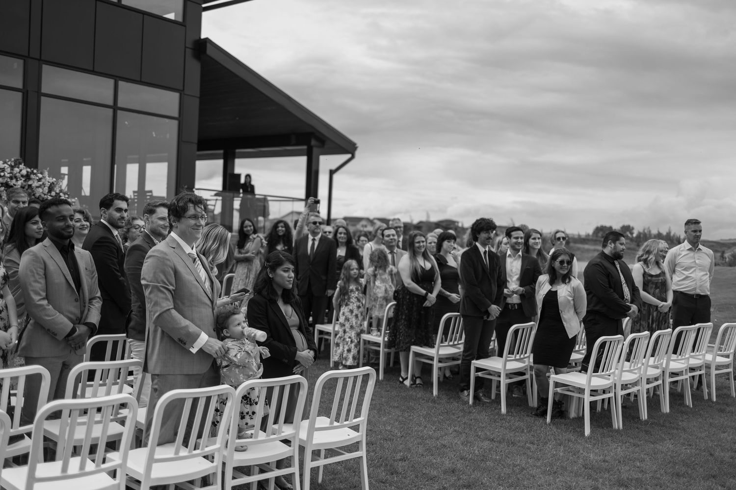 Wide shot of outdoor wedding ceremony setup with white chairs.