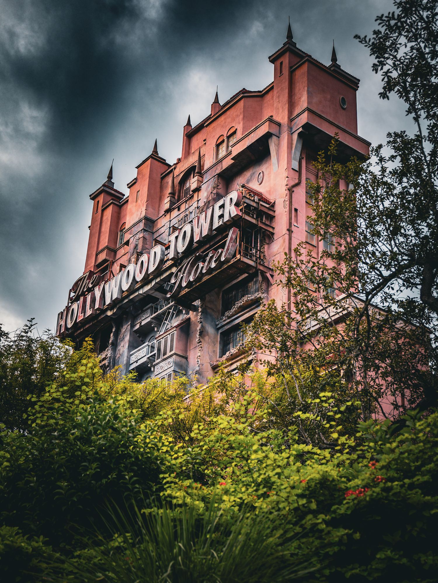Hollywood Tower Hotel sign on pink building exterior with dramatic stormy clouds.