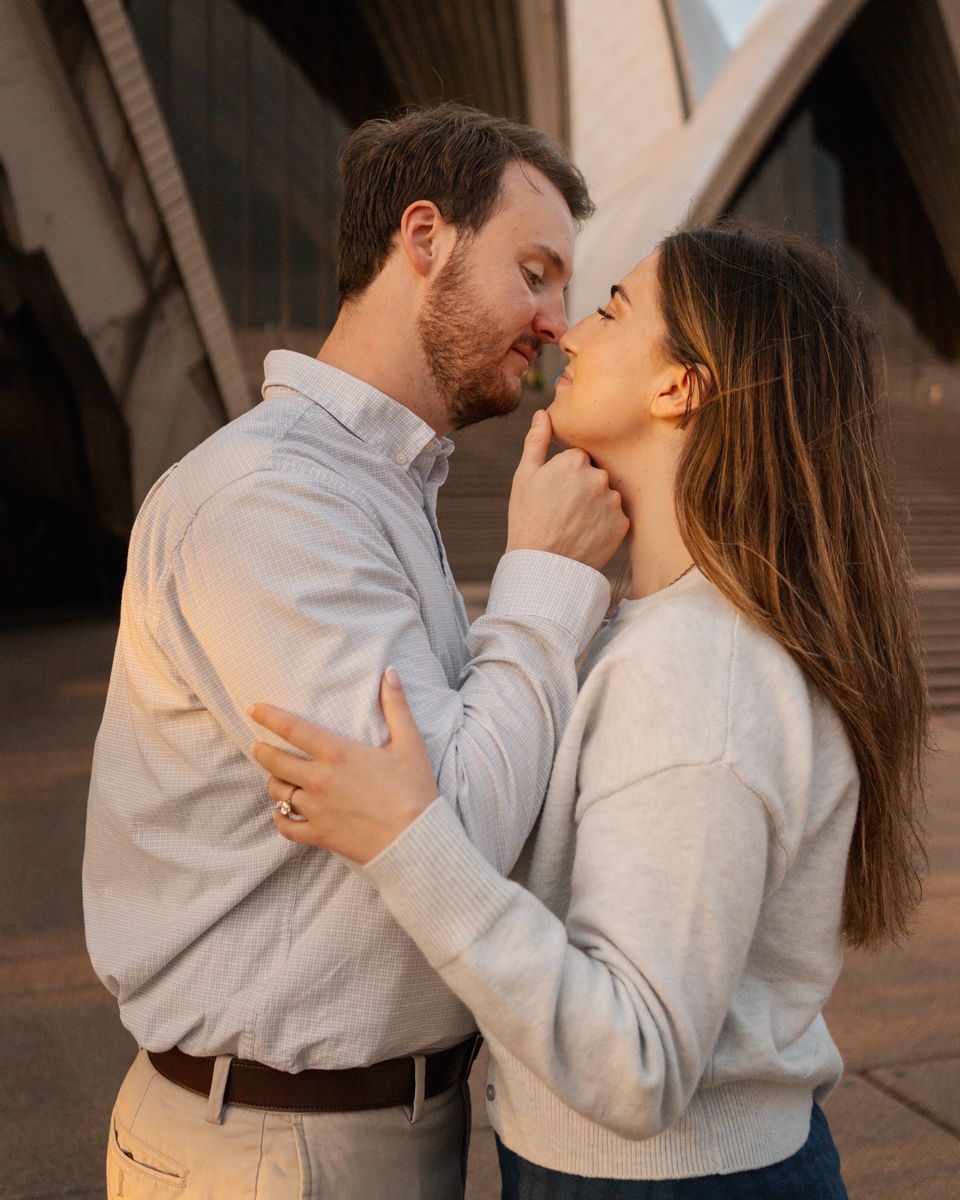 couple romantically looking at each other in front of the Sydney Opera House during the orange glow sunset light