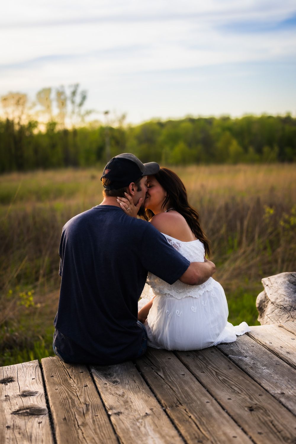 Couple sharing an intimate moment while sitting on wooden deck at sunset.