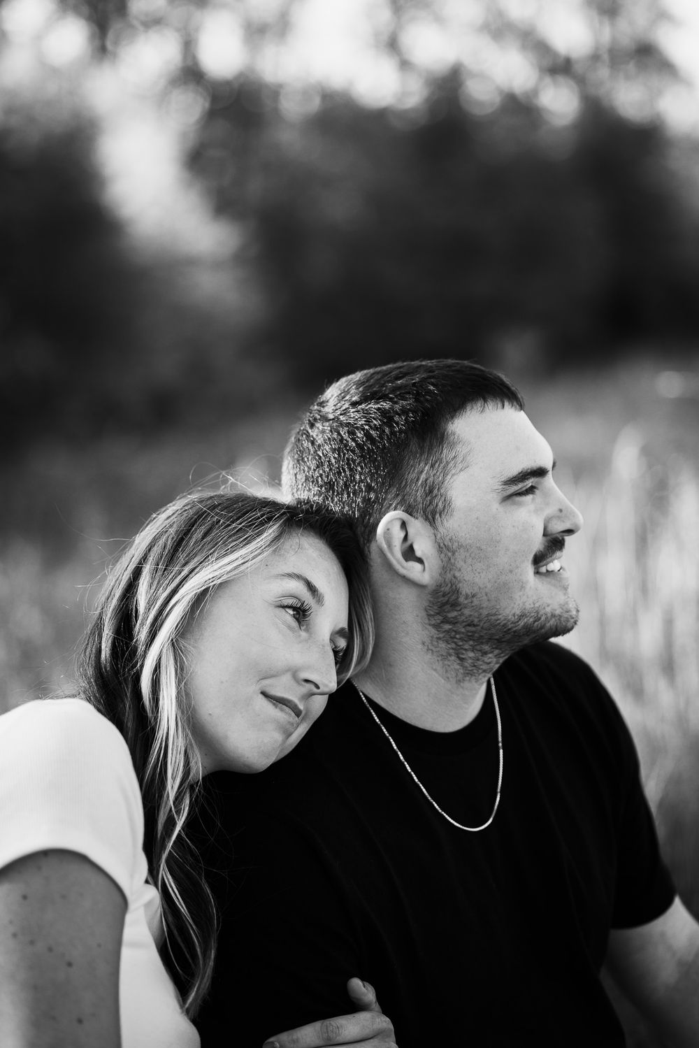Black and white portrait of couple sharing intimate moment outdoors.